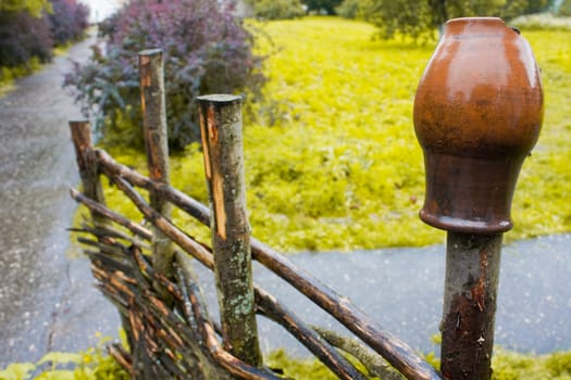 pot on wooden farm fence with grass and tree in background