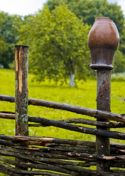 pot on wooden farm fence with grass and tree in background