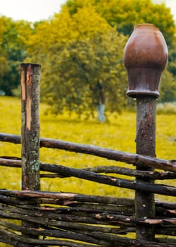 pot on wooden farm fence with grass and tree in background