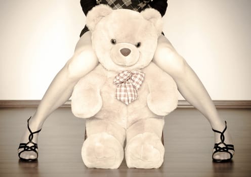 sepia photo of the toy bear between girl legs