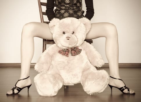 sepia photo of the toy bear between girl legs