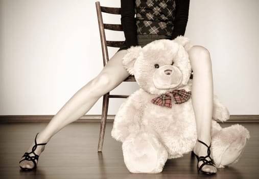 sepia photo of the toy bear between girl legs