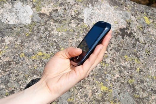 a hand using a smartphone outdoors in the nature