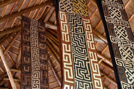 African themed fabric banners hanging from a thatch hut roof.
