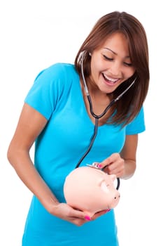 Young happy beautiful asian woman using stethoscope on her piggy bank, isolated on white background - Asian people