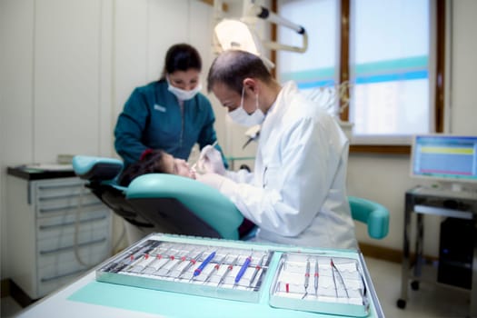 Close up of dental equipment in hospital with patient lying on couch and dentist working. Focus on foreground