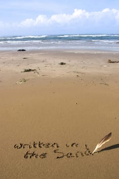 a feather used as a quill pen to write written in the sand on an irish coastal beach