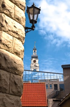 beautiful fusion of modern and old architecture in center of Riga, Latvia. Old lamp in foreground and  old tower with modern building in background with blue cloudy sky