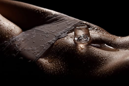 Photo shows a low-key shot of a woman's belly with an ice cube.