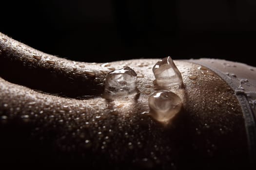 The photo shows a close-up of a back covered with water droplets and on which ice cubes lie.
