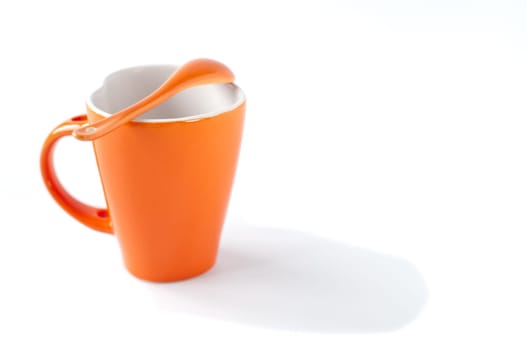 orange empty ceramic cup and spoon isolated on white