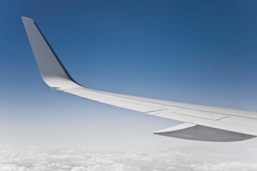 view of the jet plane wing and sky from passenger window