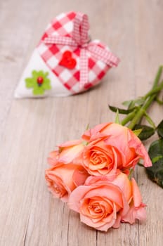 Declaration of love through orange roses and a heart made of fabric