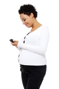 Beautiful pregnant woman dialing a number on her cellphone, isolated on a white background.