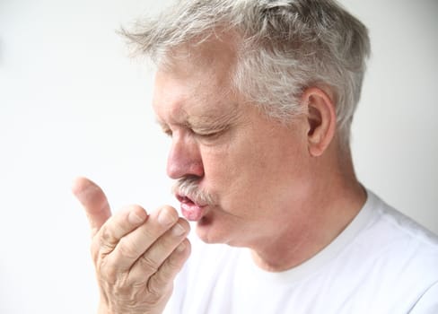 senior man sneezes into his hand