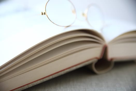 a pair of reading glasses rests on an open book