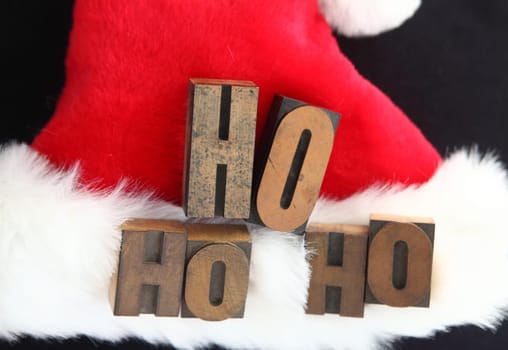 the words 'ho ho ho' in old letterpress wood type on a furry Santa Claus hat