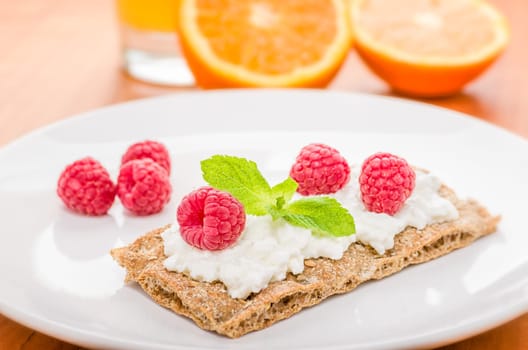 Crispbread with cream cheese and raspberries on a set breakfast table