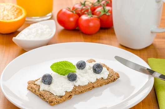 Crispbread with cream cheese and blueberries on a set breakfast table