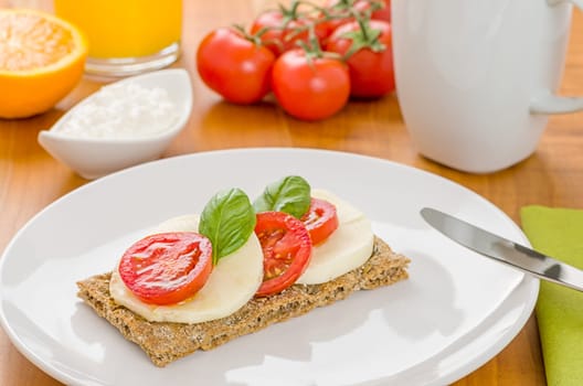 Crispbread with tomato and mozzarella on a laid breakfast table