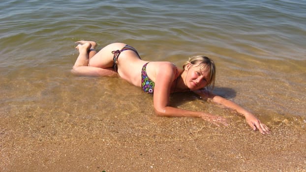 sympathetic girl lays on sand at the sea