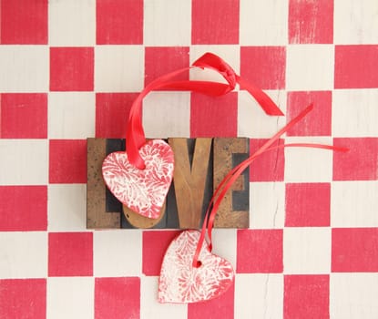 the word love repeated three times with a handmade heart ornament on a checkerboard