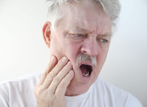 senior man with hand on his painful cheek