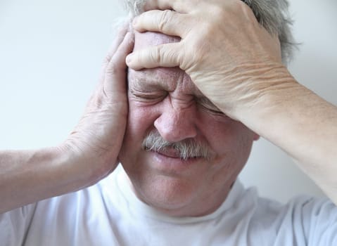 older man suffering from pounding head pain