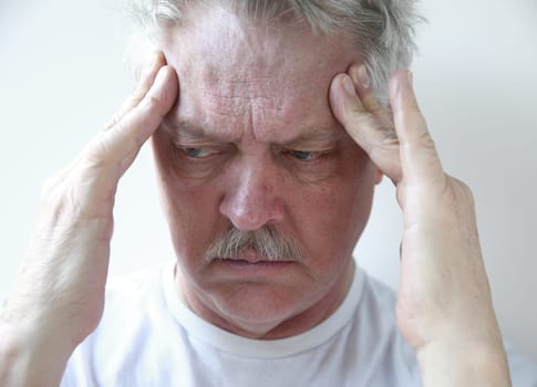 senior man with fingers on his throbbing headache pain