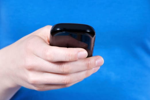 a hand using a smartphone in front of its body, blue background