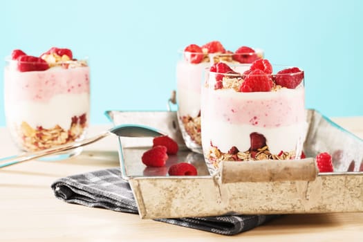 Desserts with raspberries on wood against blue background
