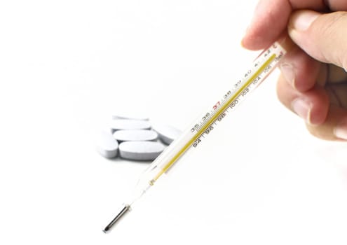 Thermometer and pills on white background