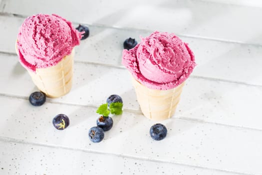 Blueberry ice cream from above on white wood with blueberries
