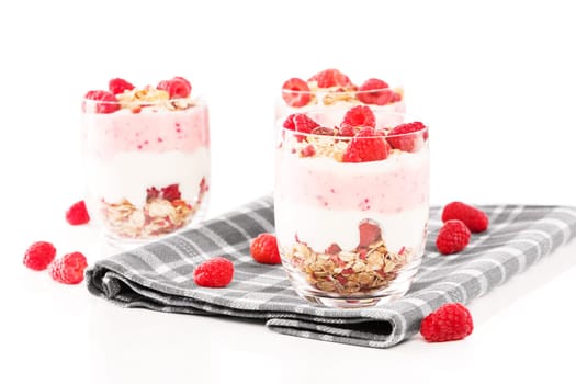 Yogurt desserts with raspberries on tea towel with white background
