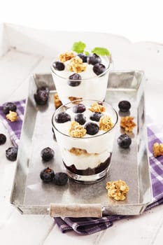 Desserts with yogurt and blueberries on metal with tea towel
