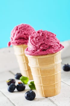 Two blueberry ice cream in waffles on white wood