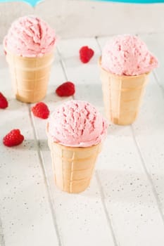 Three waffles with ice cream and raspberries on white wood