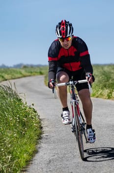Man on road bike riding down open country road.