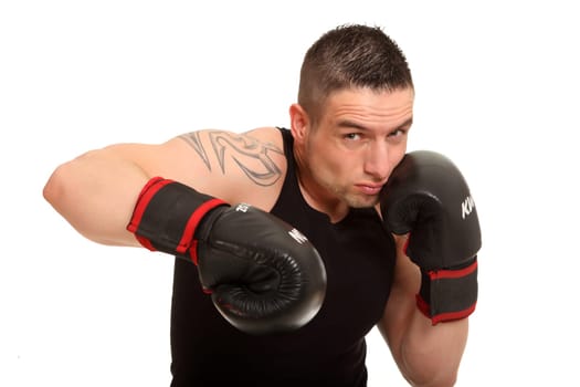Young tattooed sportsman trying to punch. He looks aggressively into the camera