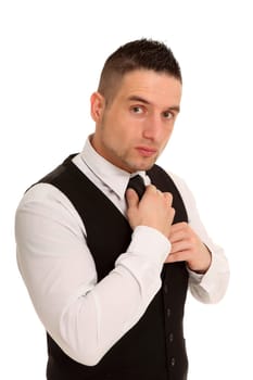 A businessman looks seriously at the camera while trying to tie a tie
