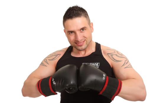 The photo shows a young man wearing boxing gloves and pressing them together. He looks kindly into the camera
