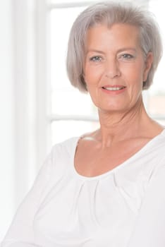 Smiling senior woman in front of a bright window
