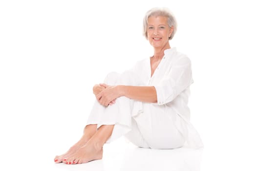 Active senior woman sitting on floor against white background