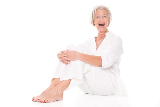 Active senior woman sitting on floor against white background