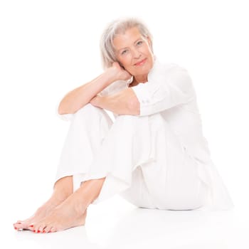 Active senior woman sitting on floor against white background