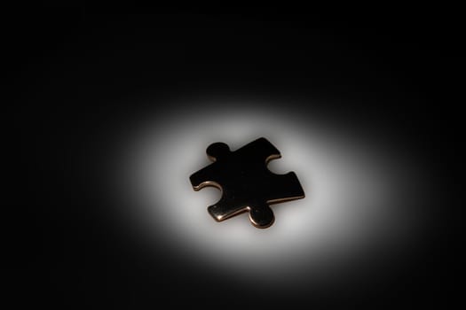 Single chrome jigsaw piece in spotlight on a black background