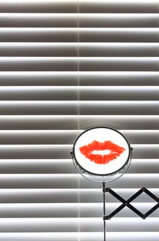 Bathroom mirror with lipstick in front of blinds with sun coming though