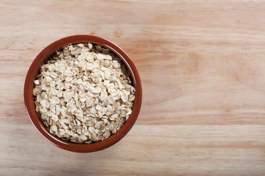 Bowl of rolled oats on wooden surface