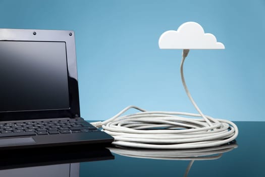 Cloud computing concept. Laptop connected to cloud via ethernet cable.