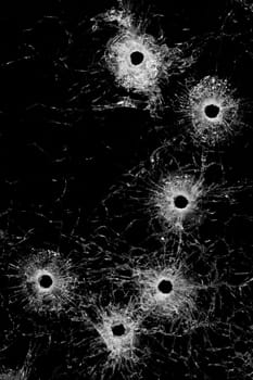 bullet holes in glass - authentic bullet holes from handgun - background or design element isolated on black